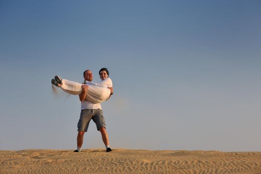 relaxed young pasionate couple enjoying the sunset  beauty on their honeymoon, on a desert with orange background