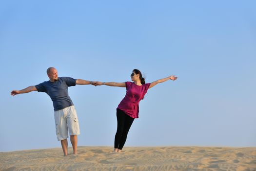 relaxed young pasionate couple enjoying the sunset  beauty on their honeymoon, on a desert with orange background