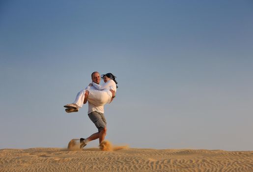 relaxed young pasionate couple enjoying the sunset  beauty on their honeymoon, on a desert with orange background