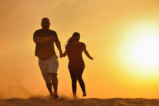 relaxed young pasionate couple enjoying the sunset  beauty on their honeymoon, on a desert with orange background