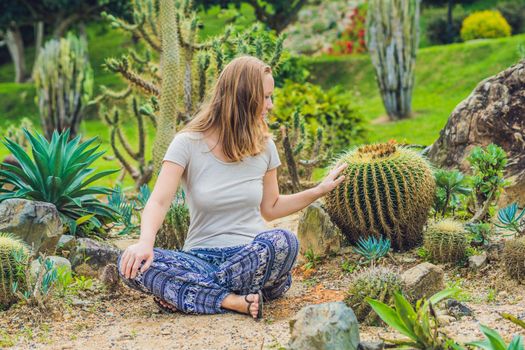 A young woman sits on the ground among the cactus. Spiny concept. Out of comfort zone concept.