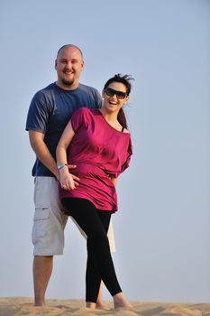 relaxed young pasionate couple enjoying the sunset  beauty on their honeymoon, on a desert with orange background