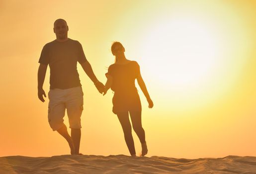 relaxed young pasionate couple enjoying the sunset  beauty on their honeymoon, on a desert with orange background