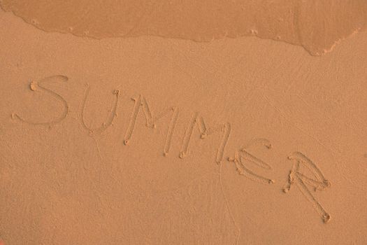 The Word Summer Written in the orange Sand background on a Beach at sunset