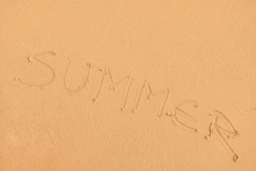 The Word Summer Written in the orange Sand background on a Beach at sunset