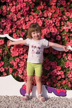 portrait of little cute girl in a flower garden in front of red flowers