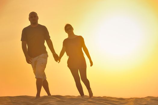 relaxed young pasionate couple enjoying the sunset  beauty on their honeymoon, on a desert with orange background