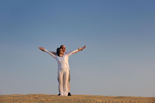 relaxed young pasionate couple enjoying the sunset  beauty on their honeymoon, on a desert with orange background