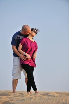 relaxed young pasionate couple enjoying the sunset  beauty on their honeymoon, on a desert with orange background