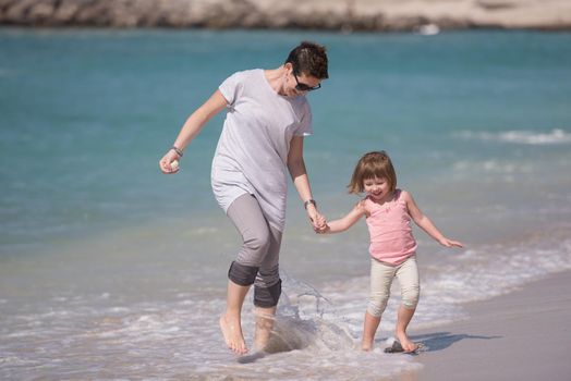 beautiful young mother and cute little girl are enjoying while running on exotic beach along the ocean Travel and Vacations.