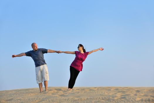 relaxed young pasionate couple enjoying the sunset  beauty on their honeymoon, on a desert with orange background