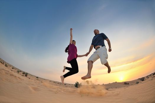 relaxed young pasionate couple enjoying the sunset  beauty on their honeymoon, on a desert with orange background