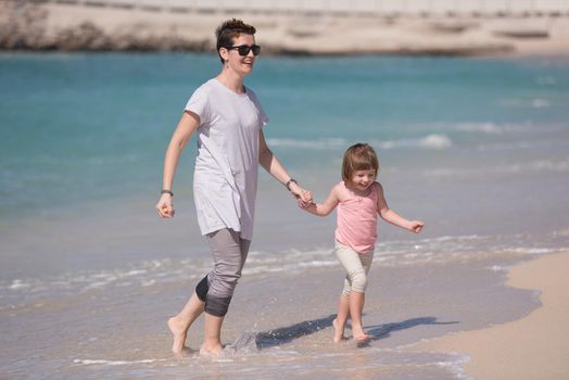 beautiful young mother and cute little girl are enjoying while running on exotic beach along the ocean Travel and Vacations.