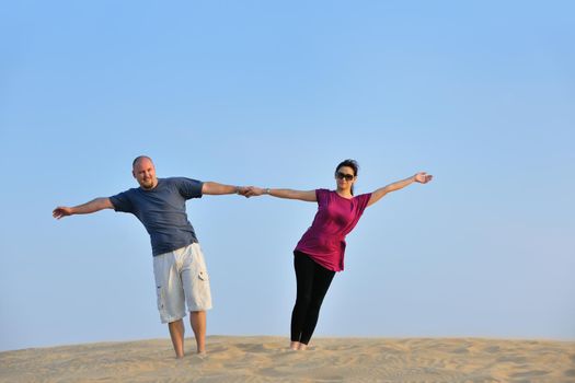 relaxed young pasionate couple enjoying the sunset  beauty on their honeymoon, on a desert with orange background