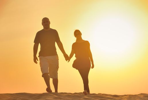 relaxed young pasionate couple enjoying the sunset  beauty on their honeymoon, on a desert with orange background