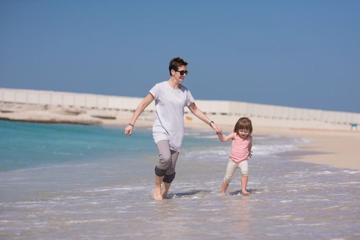 beautiful young mother and cute little girl are enjoying while running on exotic beach along the ocean Travel and Vacations.