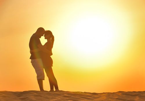 relaxed young pasionate couple enjoying the sunset  beauty on their honeymoon, on a desert with orange background