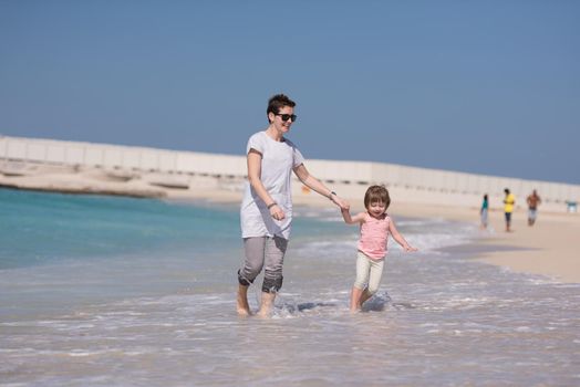 beautiful young mother and cute little girl are enjoying while running on exotic beach along the ocean Travel and Vacations.