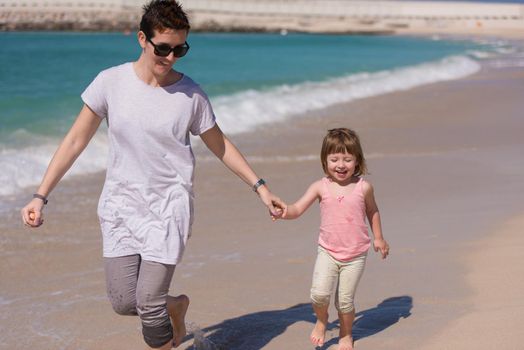 beautiful young mother and cute little girl are enjoying while running on exotic beach along the ocean Travel and Vacations.