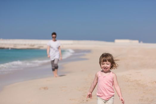 beautiful young mother and cute little girl are enjoying while running on exotic beach along the ocean Travel and Vacations.