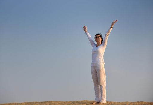 happy young woman relax and exercise yoga at desert in sunset