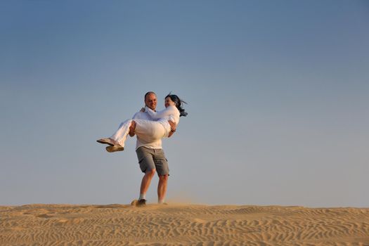 relaxed young pasionate couple enjoying the sunset  beauty on their honeymoon, on a desert with orange background