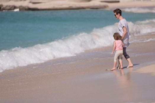 beautiful young mother and cute little girl are enjoying while running on exotic beach along the ocean Travel and Vacations.