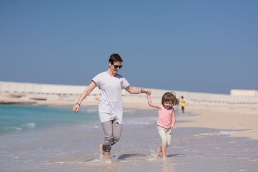 beautiful young mother and cute little girl are enjoying while running on exotic beach along the ocean Travel and Vacations.