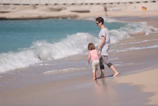 beautiful young mother and cute little girl are enjoying while running on exotic beach along the ocean Travel and Vacations.