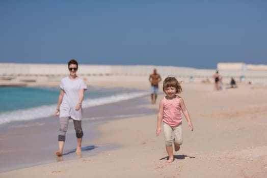 beautiful young mother and cute little girl are enjoying while running on exotic beach along the ocean Travel and Vacations.