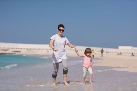 beautiful young mother and cute little girl are enjoying while running on exotic beach along the ocean Travel and Vacations.