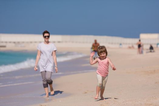 beautiful young mother and cute little girl are enjoying while running on exotic beach along the ocean Travel and Vacations.