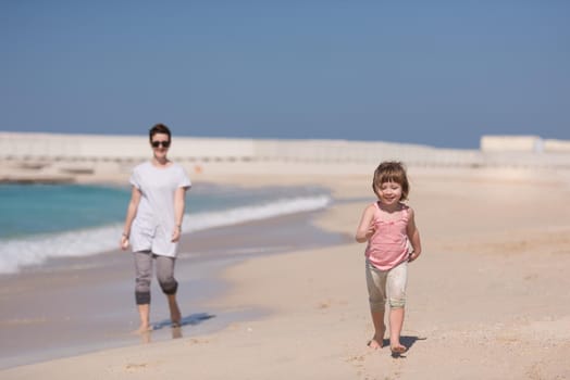 beautiful young mother and cute little girl are enjoying while running on exotic beach along the ocean Travel and Vacations.