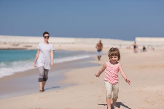 beautiful young mother and cute little girl are enjoying while running on exotic beach along the ocean Travel and Vacations.