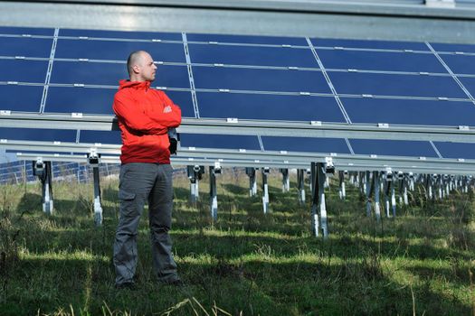 Male engineer at work place, solar panels plant industy in background