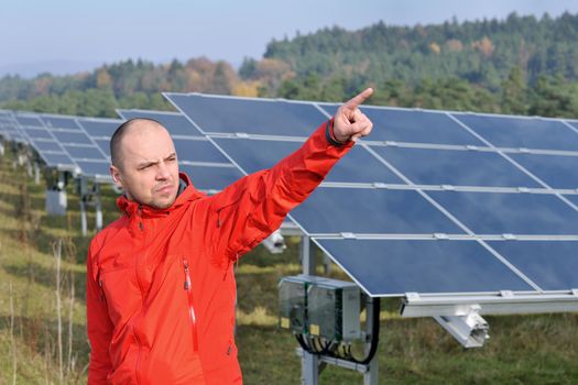 Male engineer at work place, solar panels plant industy in background