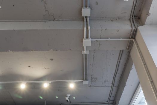 Interior architecture and ceiling design of industrial loft building decorated with modern lamps, glass windows and wall speakers