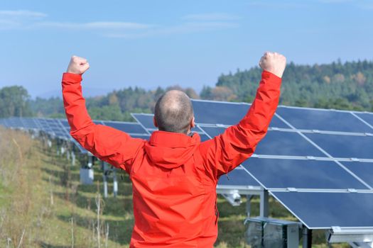 Male engineer at work place, solar panels plant industy in background