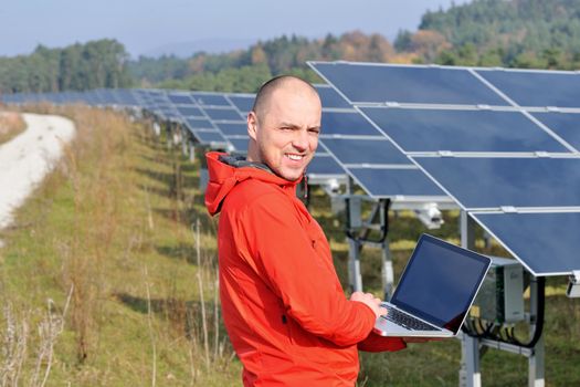 business man  engineer using laptop at solar panels plant eco energy field  in background