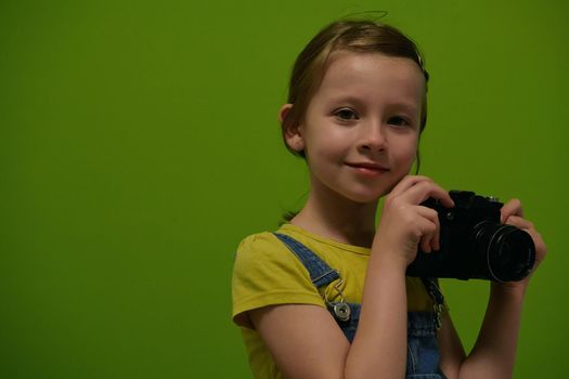 Cute little girl taking picture using vintage old retro film photo camera