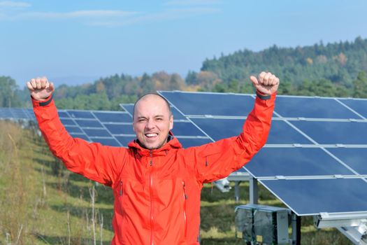 Male engineer at work place, solar panels plant industy in background