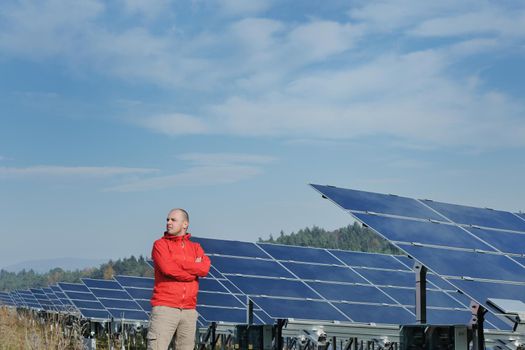 Male engineer at work place, solar panels plant industy in background