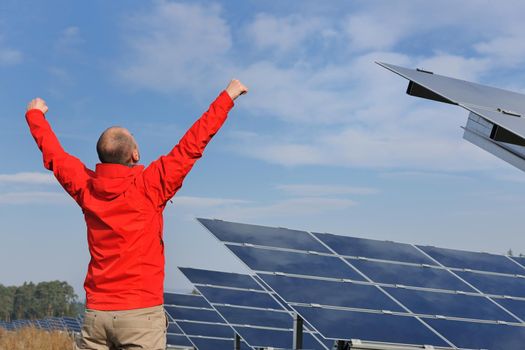 Male engineer at work place, solar panels plant industy in background