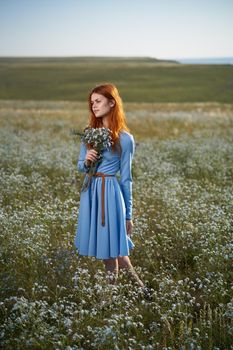 woman in a blue dress in a field in nature hat flowers walk. High quality photo