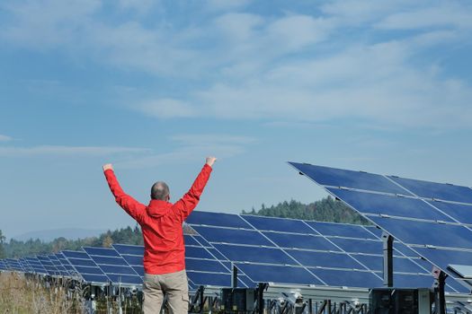 Male engineer at work place, solar panels plant industy in background