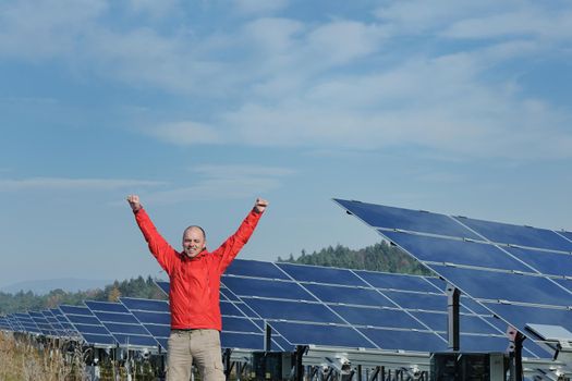 Male engineer at work place, solar panels plant industy in background