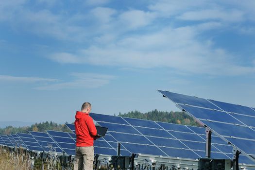 business man  engineer using laptop at solar panels plant eco energy field  in background