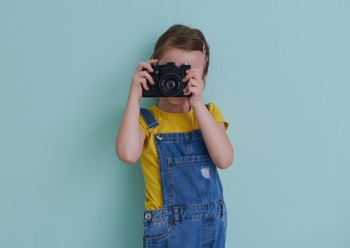 Cute little girl taking picture using vintage old retro film photo camera
