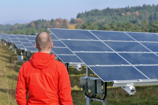 Male engineer at work place, solar panels plant industy in background