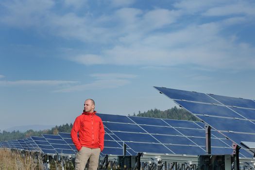 Male engineer at work place, solar panels plant industy in background